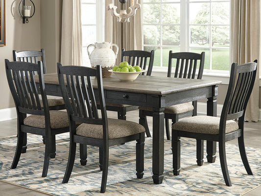 The Tyler Creek Rectangular Dining Room Table with a two-tone finish and six matching chairs, paired with a white pitcher and green apples, brightens this urban farmhouse room with large windows and beige curtains.
