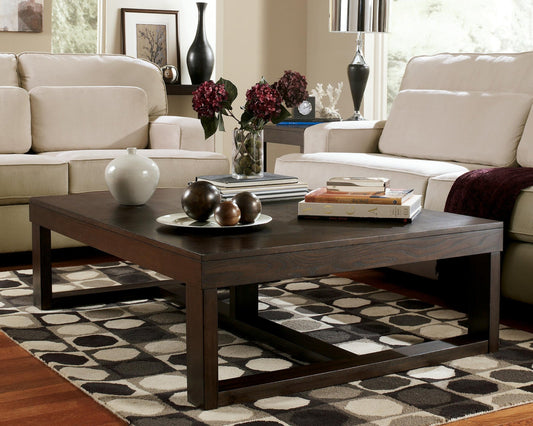 Modern living room with two beige sofas and a Watson Rectangular Cocktail Table displaying decor, books, and a vase, all arranged on a geometric-patterned rug in sleek contemporary style.