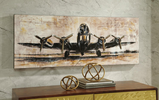 The Kalene Wall Art, featuring a vintage propeller airplane, hangs on a marble wall above a wooden cabinet decorated with gold spheres and stacked books.