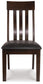 The Haddigan Dining UPH Side Chair (2/CN) features a dark wood finish, a slatted backrest, and a black faux leather upholstered seat, displayed facing forward.
