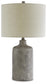 The Linus Ceramic Table Lamp (1/CN) features a textured antique black ceramic base paired with a large, cylindrical beige fabric lampshade.