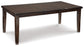 The Haddigan RECT Dining Room EXT Table is a rectangular dark wood farmhouse table with four legs, a smooth surface, and a butterfly leaf extension. Shown on a white background, it seats up to 8 for versatile gatherings.