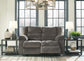 A Tulen Reclining Loveseat in gray sits between two side tables with lamps, a vase, and a plant in a bright living room with large windows.