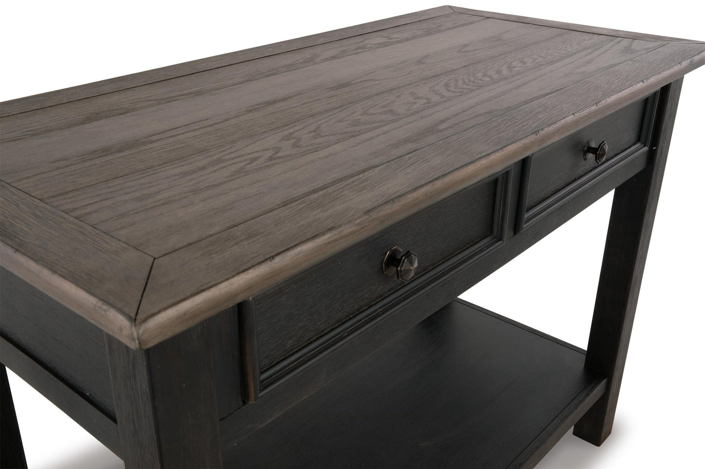 The Tyler Creek Sofa Table features a dark, weathered gray-brown finish with traditional hardware—two drawers, metal knobs, and a lower shelf—shown against a white background.