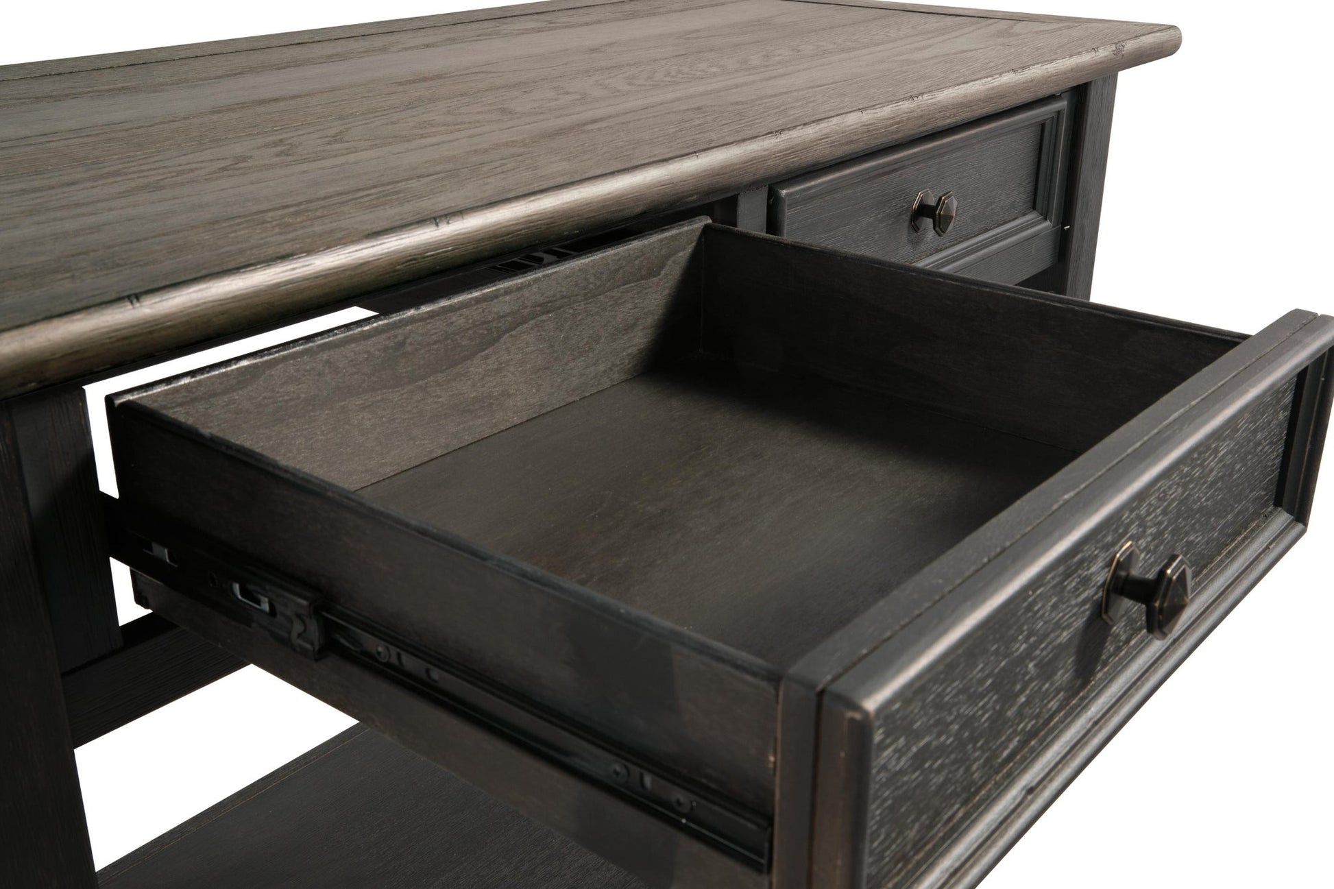 A close-up of the Tyler Creek Sofa Table shows its weathered gray-brown wood finish and an open dark wood drawer, highlighting traditional hardware on the metal slides.