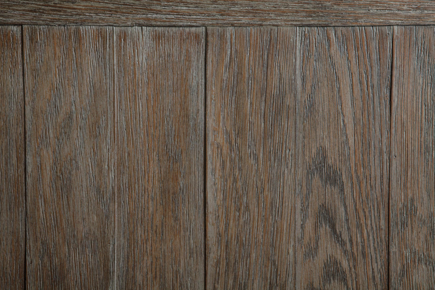 Close-up view of the Tyler Creek Sofa Table's weathered gray-brown wood surface with vertical planks and a natural brown grain pattern.