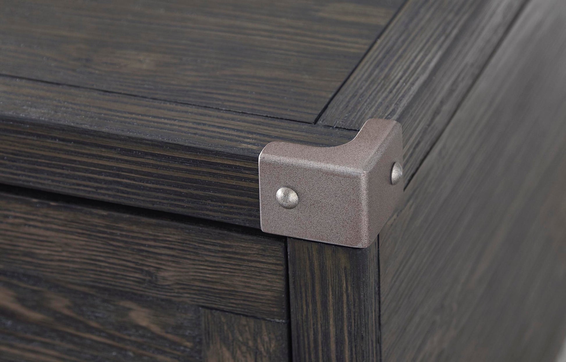 Close-up of the corner of the Todoe Lift Top Cocktail Table, featuring a weathered pine finish and a dark wooden box design with a metal corner bracket secured by two screws.