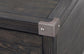 Close-up of the corner of the Todoe Lift Top Cocktail Table, featuring a weathered pine finish and a dark wooden box design with a metal corner bracket secured by two screws.