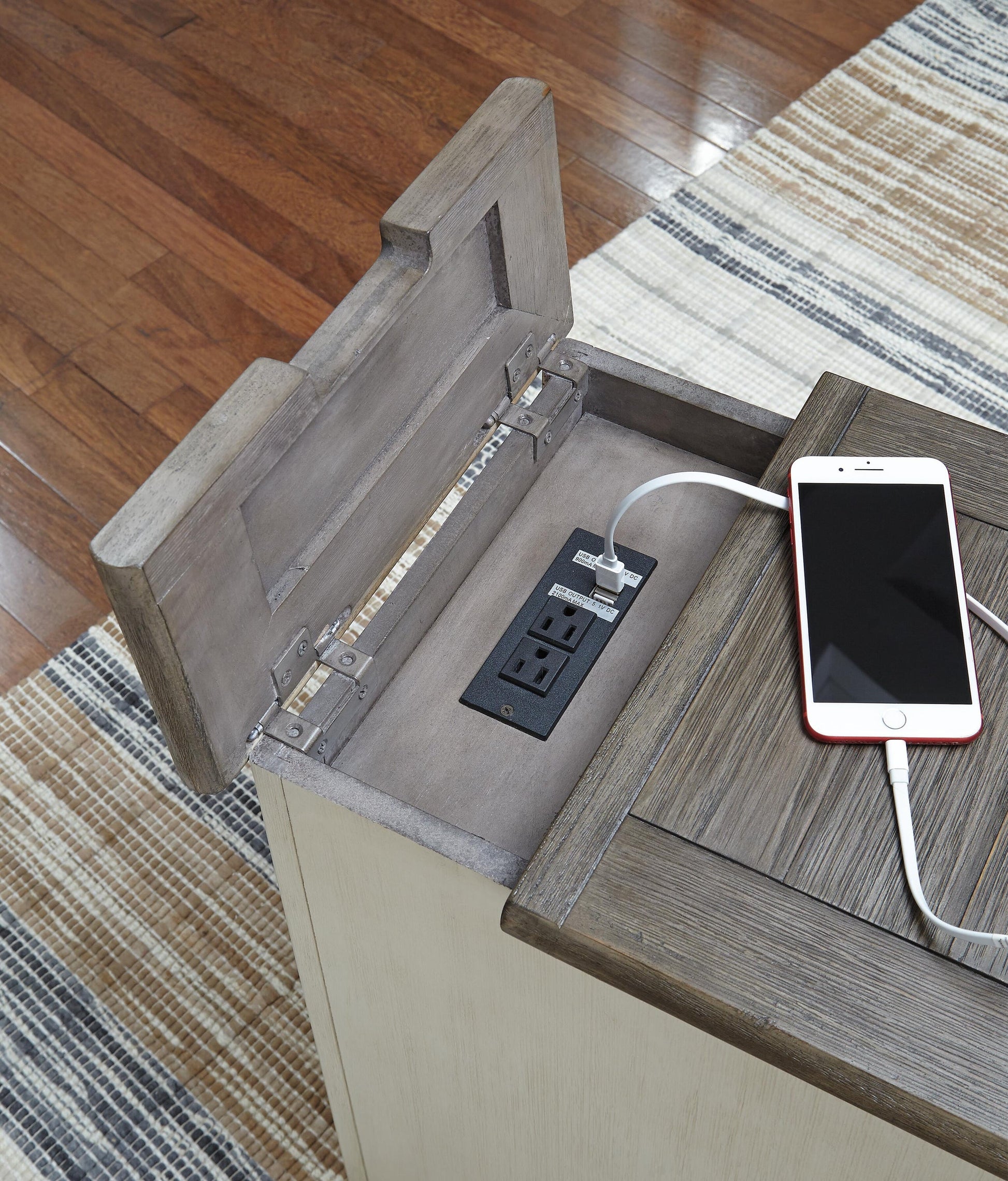 The Bolanburg Chair Side End Table in antique white offers an open compartment with two power outlets and two USB ports, perfect for charging devices like a smartphone via USB cable.