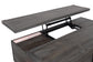 A close-up of the Todoe Lift Top Cocktail Table showcases its rustic-industrial style, weathered pine finish, and partially raised top revealing sturdy metal hardware beneath.
