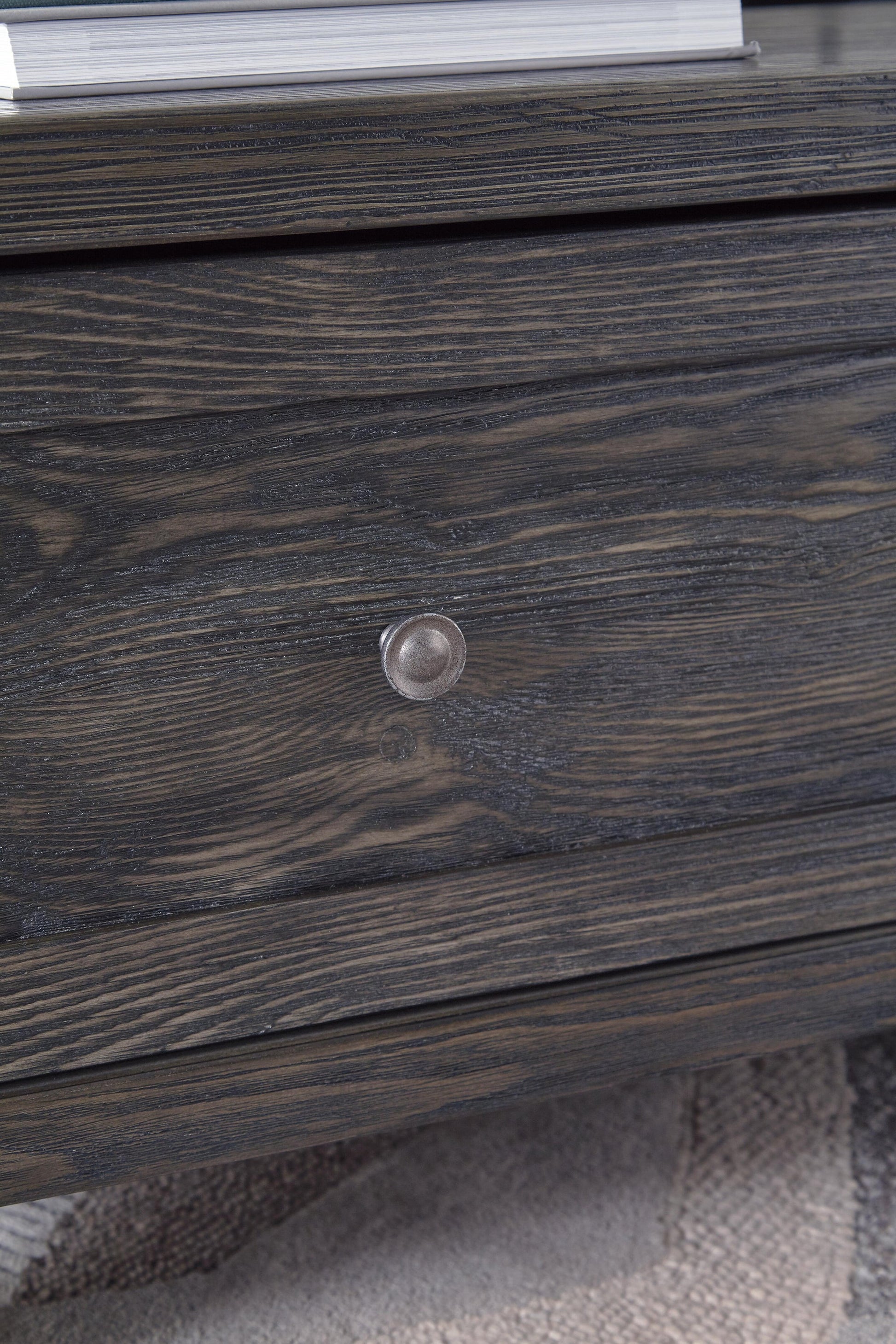 Close-up of a dark wooden drawer with a round metal knob on the Todoe Lift Top Cocktail Table, with part of a textured rug visible underneath.