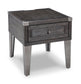 The Todoe Rectangular End Table features a rustic-industrial design with metal legs, a front drawer, and metal corner accents on the tabletop.