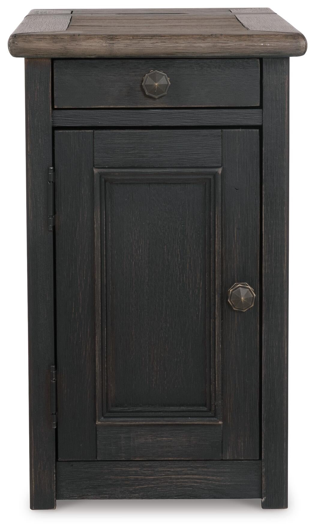 The Tyler Creek Chair Side End Table features a weathered gray-brown rustic finish, dark wood, round metal knobs, a top drawer, lower door, and a built-in charging station for added convenience.