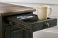 A close-up of the Tyler Creek Chair Side End Table, featuring a weathered gray-brown finish and a pull-out tray with a pen, pencil, and mug.