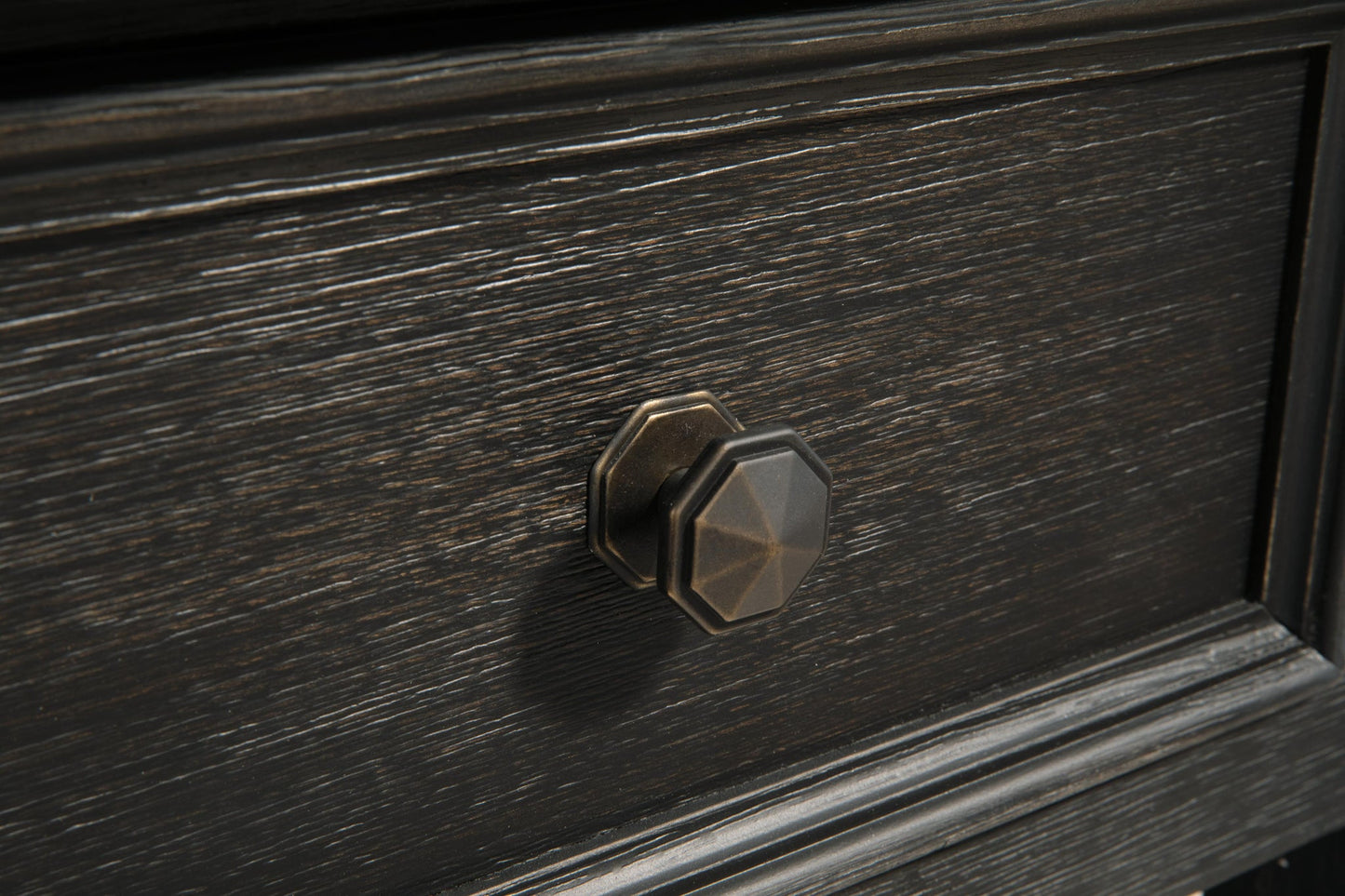 Close-up of a dark wood drawer on the Tyler Creek Rectangular End Table, featuring a geometric brass-colored knob at the center and a weathered gray-brown tabletop.
