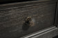 Close-up of a dark wood drawer on the Tyler Creek Rectangular End Table, featuring a geometric brass-colored knob at the center and a weathered gray-brown tabletop.