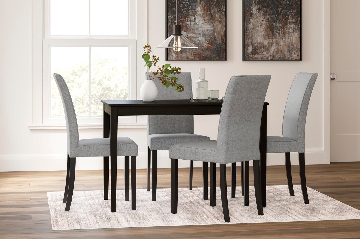 A modern dining room featuring the Kimonte Rectangular Dining Room Table in dark brown, four light gray upholstered chairs, a white vase with greenery, glassware, and two abstract wall paintings.