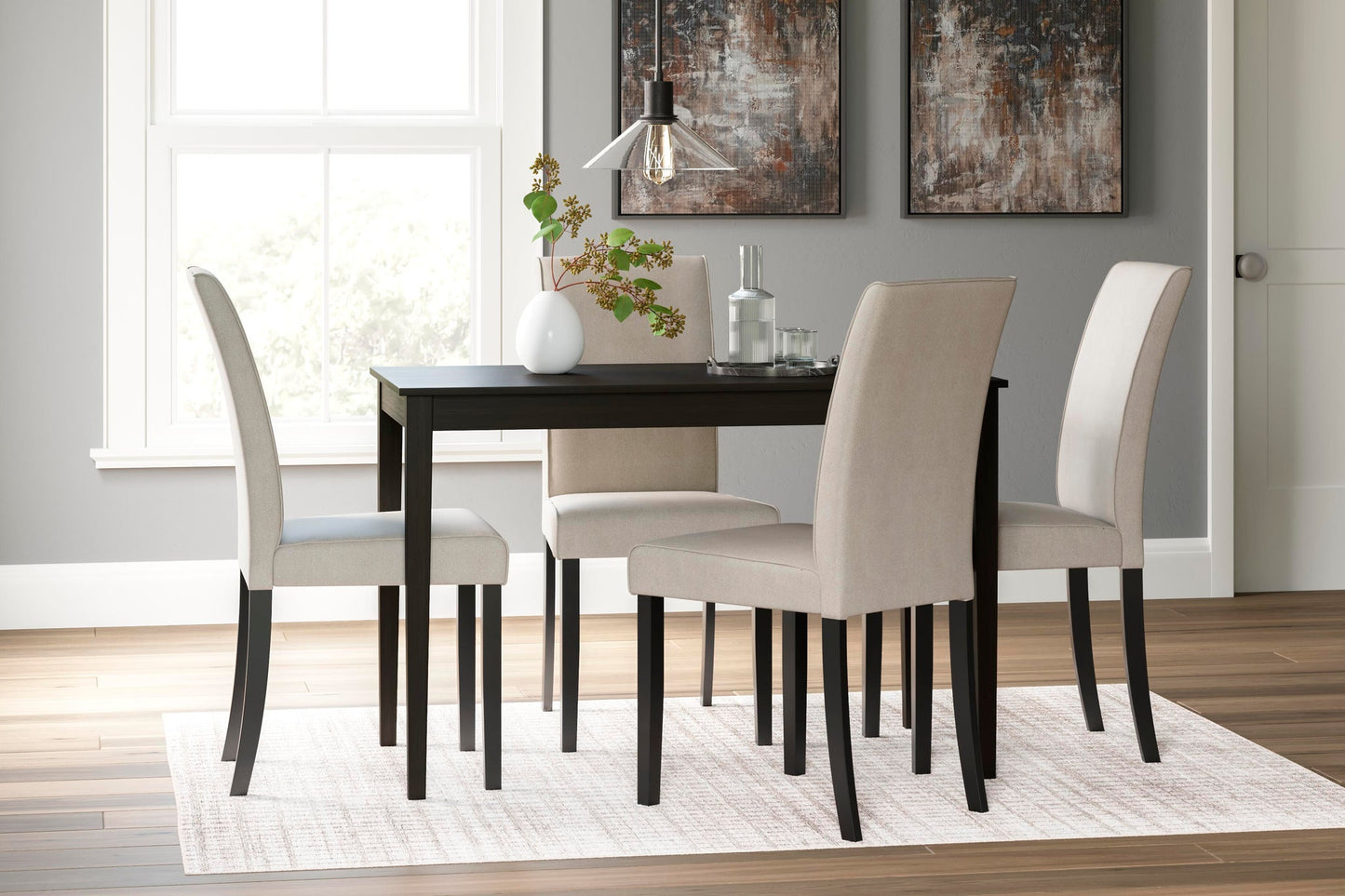 A modern dining room with the Kimonte Rectangular Dining Room Table in dark brown, four beige upholstered chairs, a white rug, minimalist decor, and abstract art on gray walls.