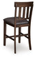 The Haddigan Upholstered Barstool (2/CN) features a dark-finished wooden frame, padded brown faux leather seat, classic slat back design, and a convenient footrest.