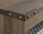 Close-up of the Trinell LG TV Stand w/Fireplace Option, showcasing a reclaimed barn wood corner with a metal bracket and decorative rivets, set atop a patterned black and white floor.