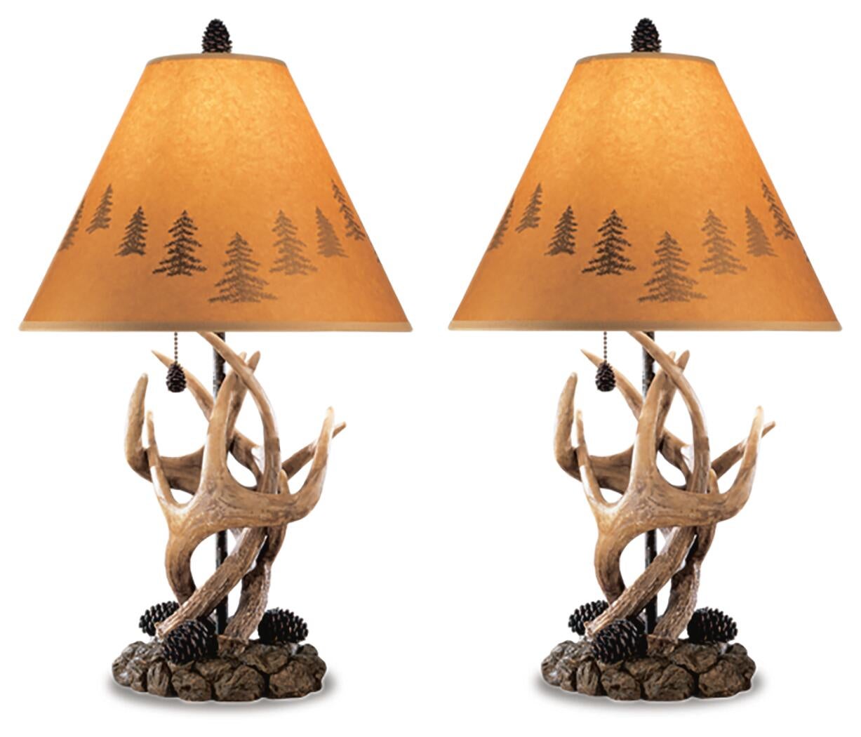 The Derek Poly Table Lamp (set of 2) features antler and pinecone details with tan lampshades showcasing tree silhouettes, adding a cozy mountain retreat style to any room.