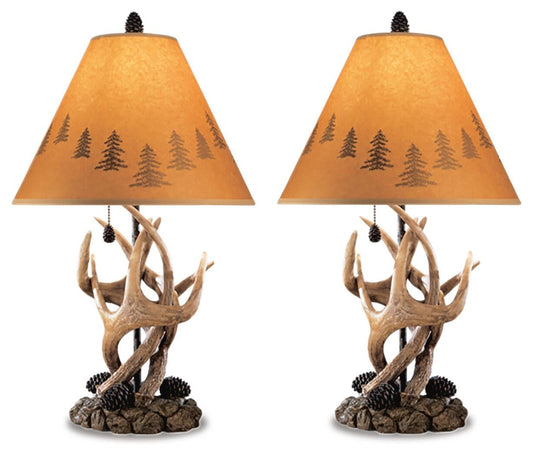 The Derek Poly Table Lamp (set of 2) features antler and pinecone details with tan lampshades showcasing tree silhouettes, adding a cozy mountain retreat style to any room.