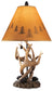 The Derek Poly Table Lamp (2/CN) features an antler-inspired base, pine cone accents, and a tan shade with dark tree silhouettes—an ideal choice to bring mountain retreat style to your space.