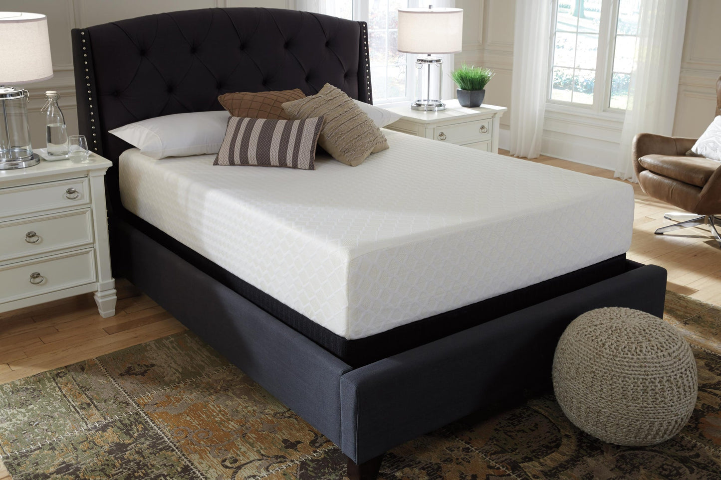 A neatly made bed features the Chime 12 Inch Memory Foam Mattress and several pillows, with two white nightstands and lamps on each side, set in a bright, well-lit bedroom.