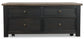 The Tyler Creek Lift Top Cocktail Table features a dark wood finish, four drawers with metal knobs, and small wheels—ideal as a stylish storage coffee table for your living room.