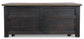 The Tyler Creek Lift Top Cocktail Table features a dark wood finish, a flat lid, four front rectangular panels, and small wheels at the base for easy mobility.
