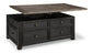 The Tyler Creek Lift Top Cocktail Table features a dark wood finish, four drawers, and a partially raised lift-top surface that reveals spacious internal storage.