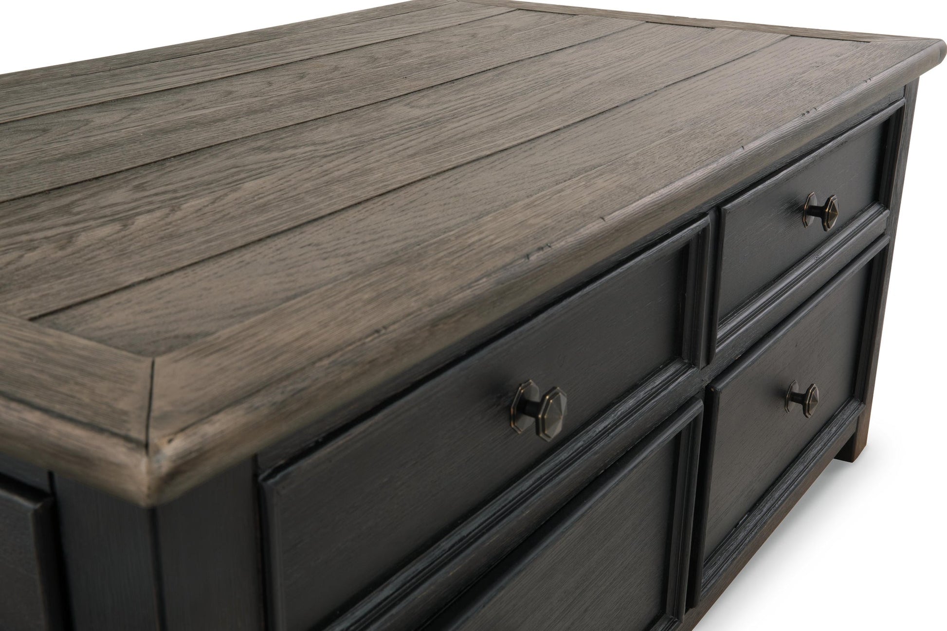 A close-up of the Tyler Creek Lift Top Cocktail Table showcases its dark wood finish, textured grain top, and metal knobs, echoing a shabby chic style.