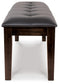 The Haddigan Large UPH Dining Room Bench features a black tufted cushion and dark wooden legs, providing stylish front-facing bench seating for any dining area.