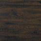 The Rokane Dining Room Table Set (7/CN) features a dark brown wood surface with visible grain patterns and distressed markings, ideal for pairing with upholstered chairs or as a complete dining table set.