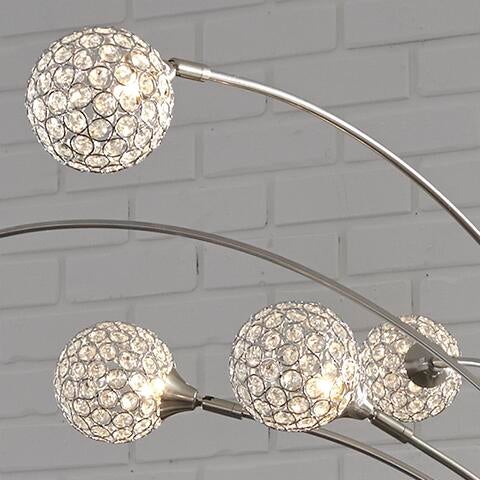The Winter Metal Arc Lamp (1/CN) features four crystal acrylic spheres on curved metal arms, set against a white brick wall for a modern, elegant look.