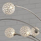 The Winter Metal Arc Lamp (1/CN) features four crystal acrylic spheres on curved metal arms, set against a white brick wall for a modern, elegant look.