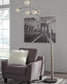 A gray armchair with a white fluffy pillow sits next to the Winter Metal Arc Lamp, featuring five lights and crystal acrylic balls, in front of a black-and-white Brooklyn Bridge photo on a white brick wall.