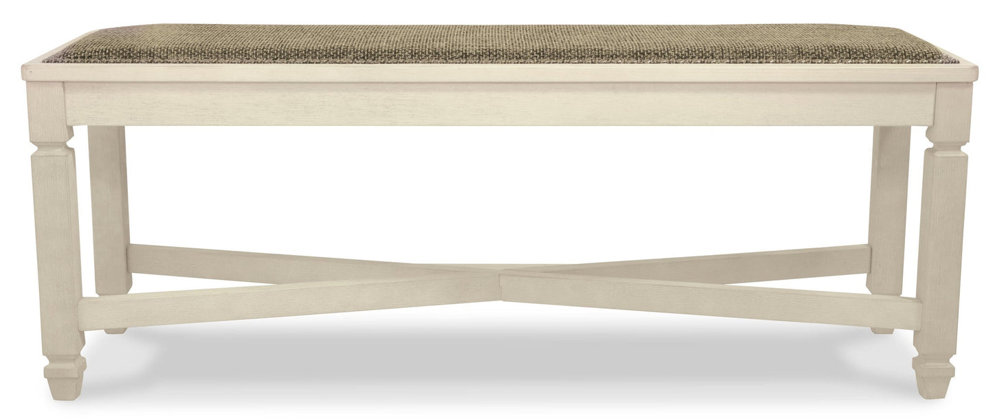 The Bolanburg Large UPH Dining Room Bench features a cushioned, textured rectangular seat and a white wooden frame with cross-braced legs in an antiqued white finish.