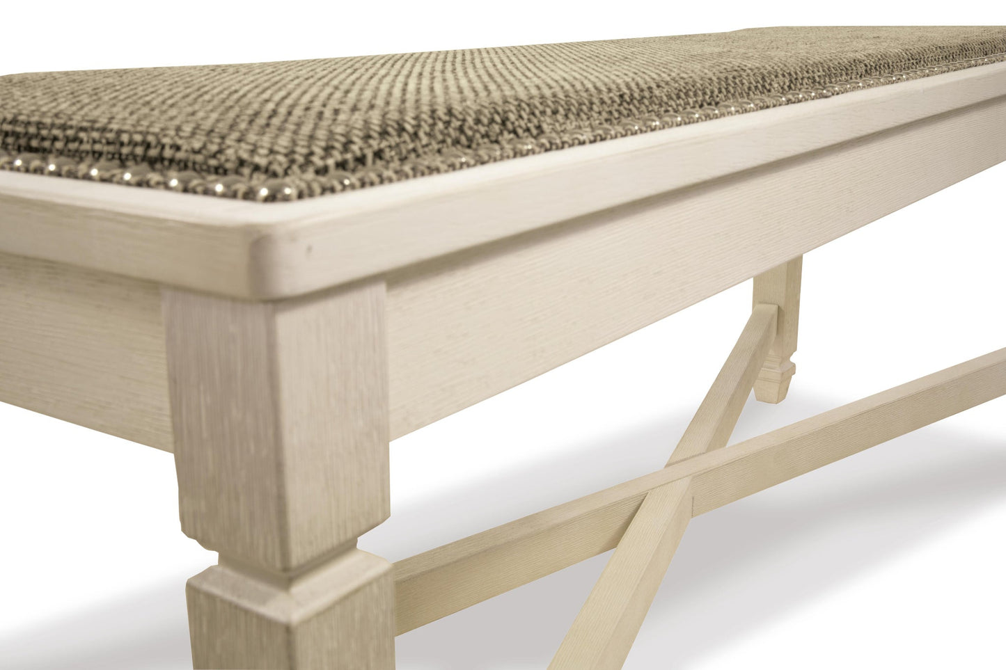 A close-up of the Bolanburg Large UPH Dining Room Bench, showcasing its antiqued white finish, textured heavy woven fabric seat, and decorative nailhead trim.