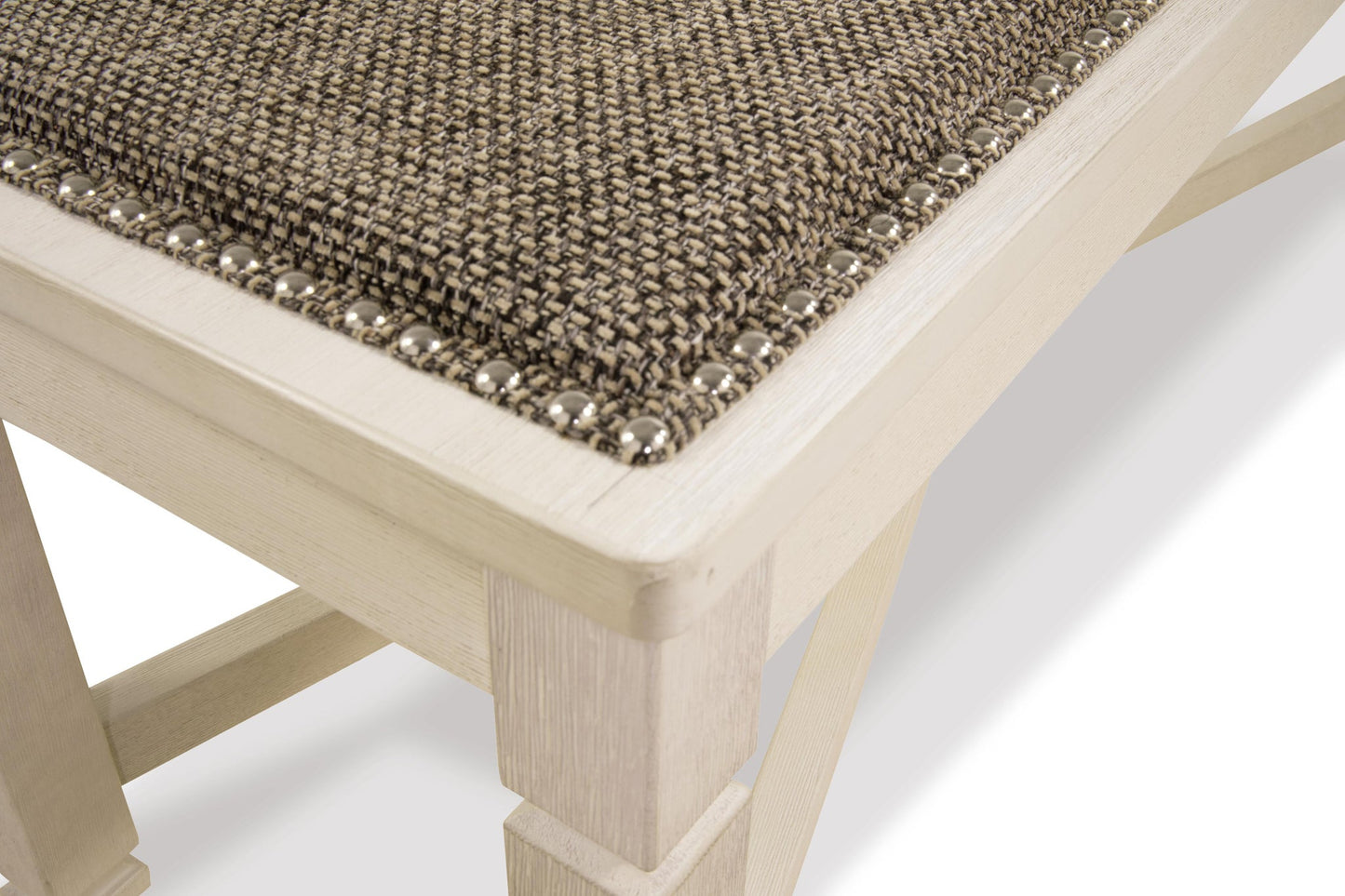 Close-up of the Bolanburg Large UPH Dining Room Bench featuring an antiqued white light wood frame, textured brown heavy woven fabric seat, and decorative metal studs along the edge.