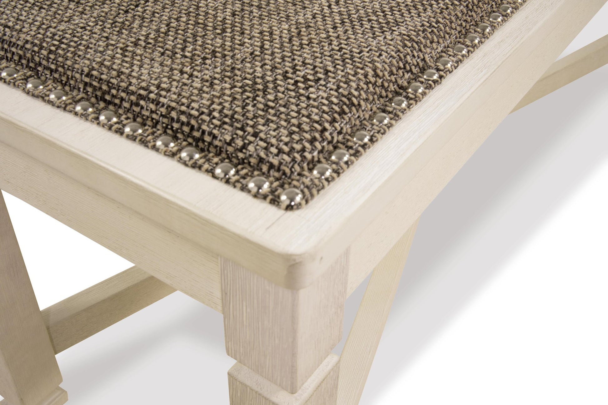 Close-up of the Bolanburg Large UPH Dining Room Bench featuring an antiqued white light wood frame, textured brown heavy woven fabric seat, and decorative metal studs along the edge.