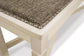 Close-up of the Bolanburg Large UPH Dining Room Bench featuring an antiqued white light wood frame, textured brown heavy woven fabric seat, and decorative metal studs along the edge.