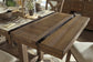 The Moriville RECT DRM Counter EXT Table, a wooden extendable dining table with its extension leaf partially pulled out, is set with dishes, utensils, and potted plants.