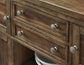 Close-up of the Moriville Dining Room Server featuring four drawers with antiqued bronze-tone hardware and a white dish displayed on the lower shelf.