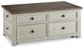 The Bolanburg Lift Top Cocktail Table features a rectangular dark wood top, antique white finish base, and four front storage drawers with black knobs.