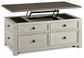 The Bolanburg Lift Top Cocktail Table features an antique white finish, four front storage drawers, and a partially raised top revealing hidden storage—blending style and function for your living space.
