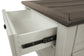 A close-up shows the Bolanburg Lift Top Cocktail Table’s wooden storage drawer, partially open to reveal metal sliding hardware. The table features an antique white finish with a contrasting dark wood top.