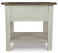 The Bolanburg Rectangular End Table features a two-tone distressed finish with a dark top, light-colored legs, lower shelf, and smooth-gliding drawer, shown from the front.