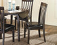 A dark wood dining table with four Hammis Dining UPH Side Chairs, two blue candlesticks, a mug, and a newspaper set on a beige rug in a bright room.