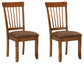Two Berringer Dining UPH Side Chairs (2/CN) with cushioned brown microfiber seats and wooden spindle backs are placed side by side against a white background.